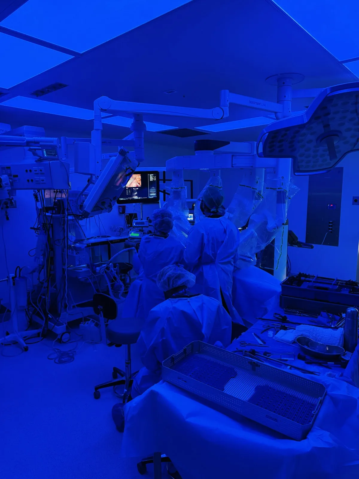 Equipo quirúrgico en el quirófano con iluminación azul durante una cirugía robótica