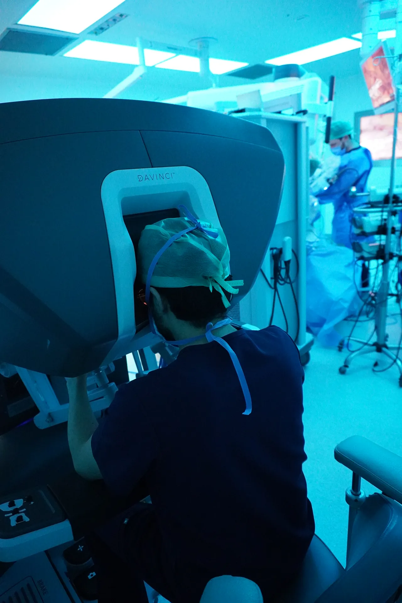Cirujano operando en la consola del robot Da Vinci en un quirófano con luz azul